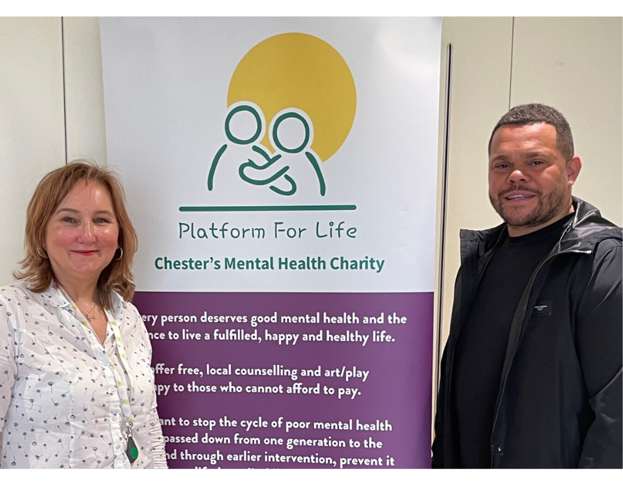 Ceri George, Platform for Life CEO with Chris Larsen, Founder of Leap 76 standing together smiling in front of Platform for Life signage.
